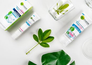 รูปรวมผลิตภัณฑ์ของการ์นิเย่ เพียวแอคทีฟ เซนสิทีฟ สำหรับผิวอ่อนโยน พื้นหลังเป็นใบไม้สีเขียว